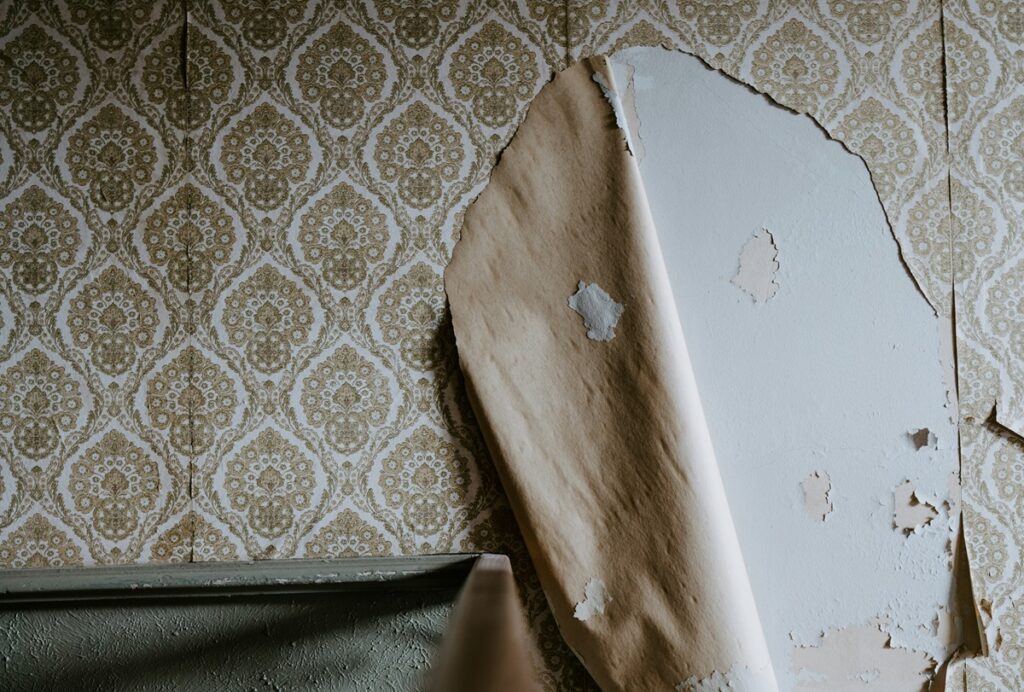 Peeling wallpaper and damaged wall surface showing signs of hidden moisture inside a wall