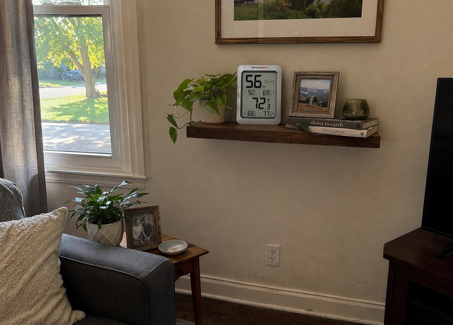 Digital hygrometer placed on a shelf in a living room at proper height for accurate humidity measurement