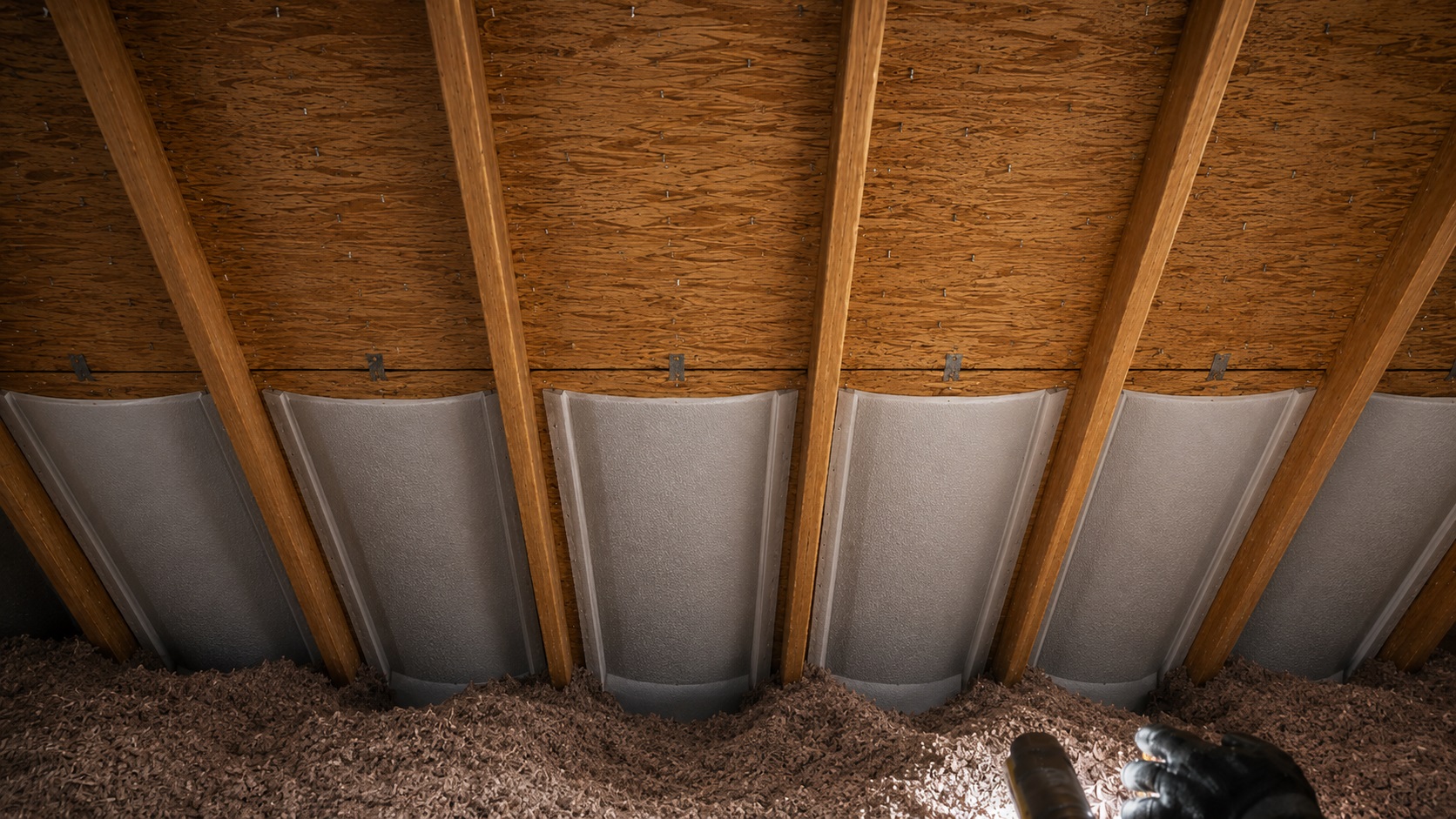 Attic ventilation baffles installed between rafters with insulation pulled back to keep soffit airflow paths open.