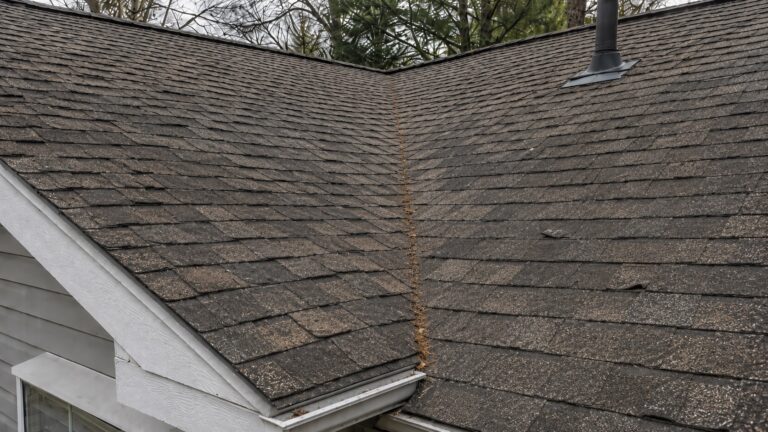 Aging asphalt roof with faded shingles, granule loss, lifted edges, and light debris collecting in a worn roof valley.