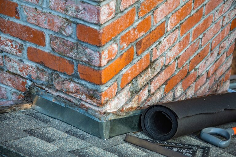 Brick chimney with worn mortar joints showing gaps where rainwater can enter the masonry