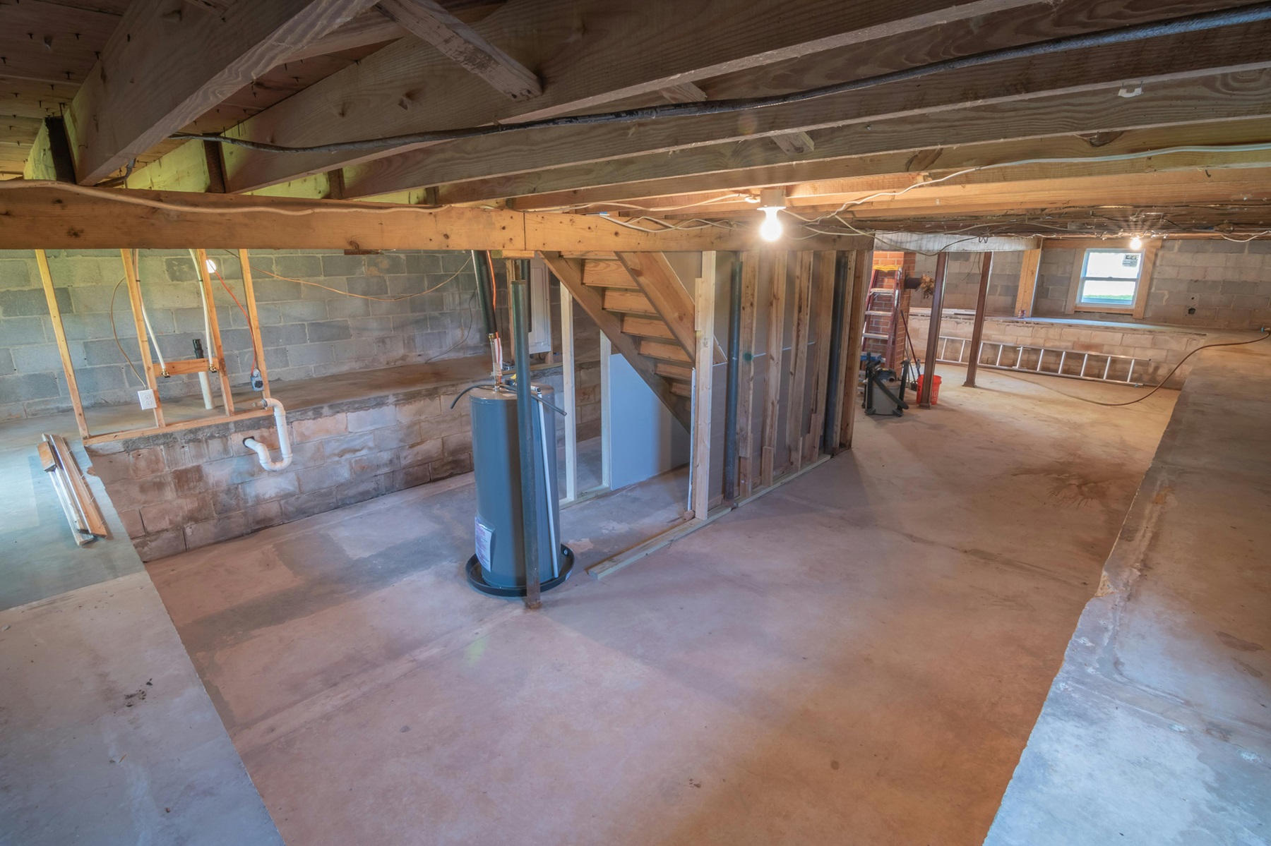 Unfinished basement with a water heater, concrete floor, and areas where moisture problems may appear