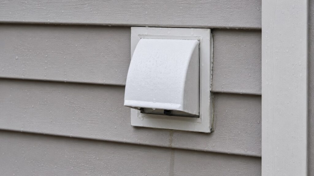 Exterior wall penetration showing subtle moisture risk around a cable, vent, or faucet opening after rain.