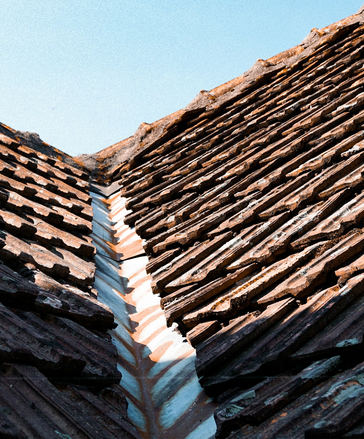 Rusted metal roof valley between tile roof sections showing signs the roof valley may be failing