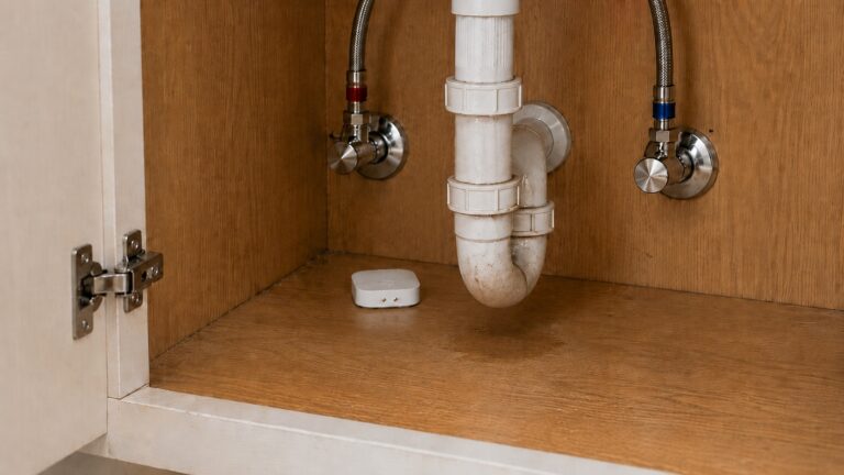 Smart water leak detector placed under a sink cabinet for early leak alerts